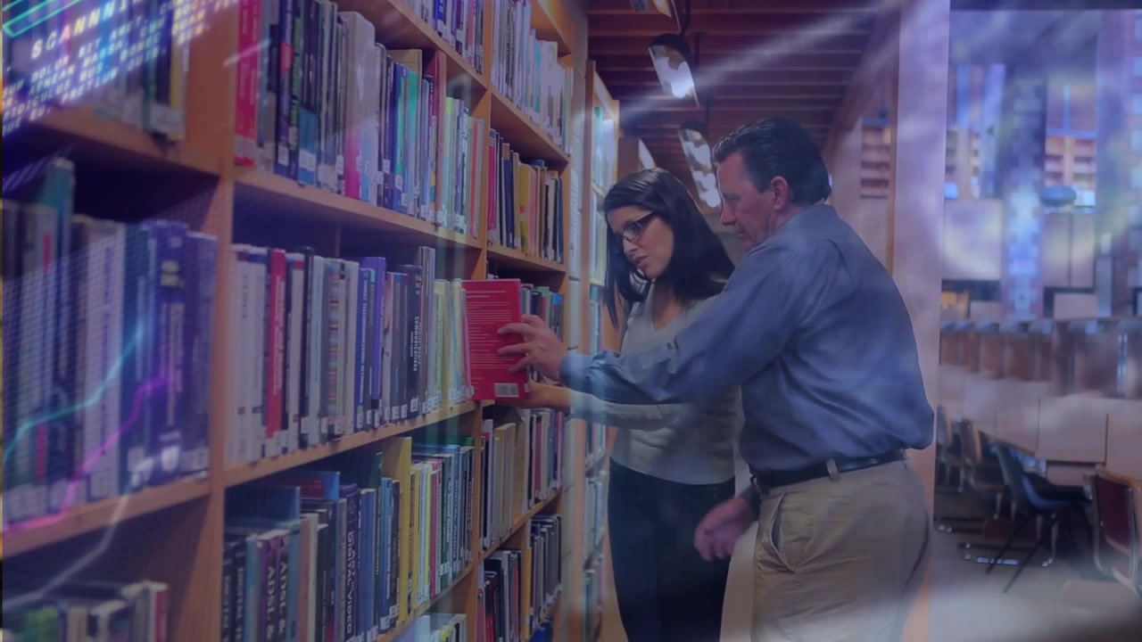 Colleghi accademici che esaminano gli scaffali di legno della biblioteca e selezionano un libro rosso per uno studio collaborativo.