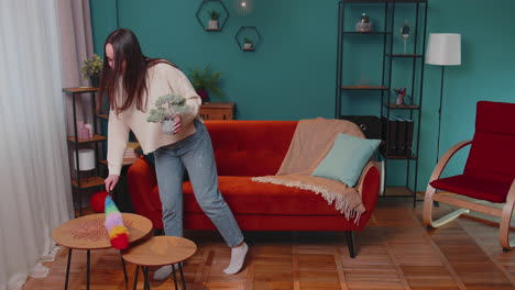 Happy-young-woman-dusting-furniture-caring-for-hygiene-using-colorful-duster-in-living-room-at-home