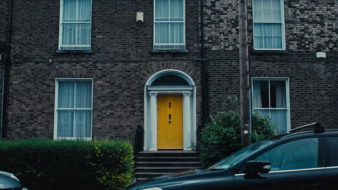 A traditional Irish house with a yellow door, brick walls, windows, and a charming exterior.