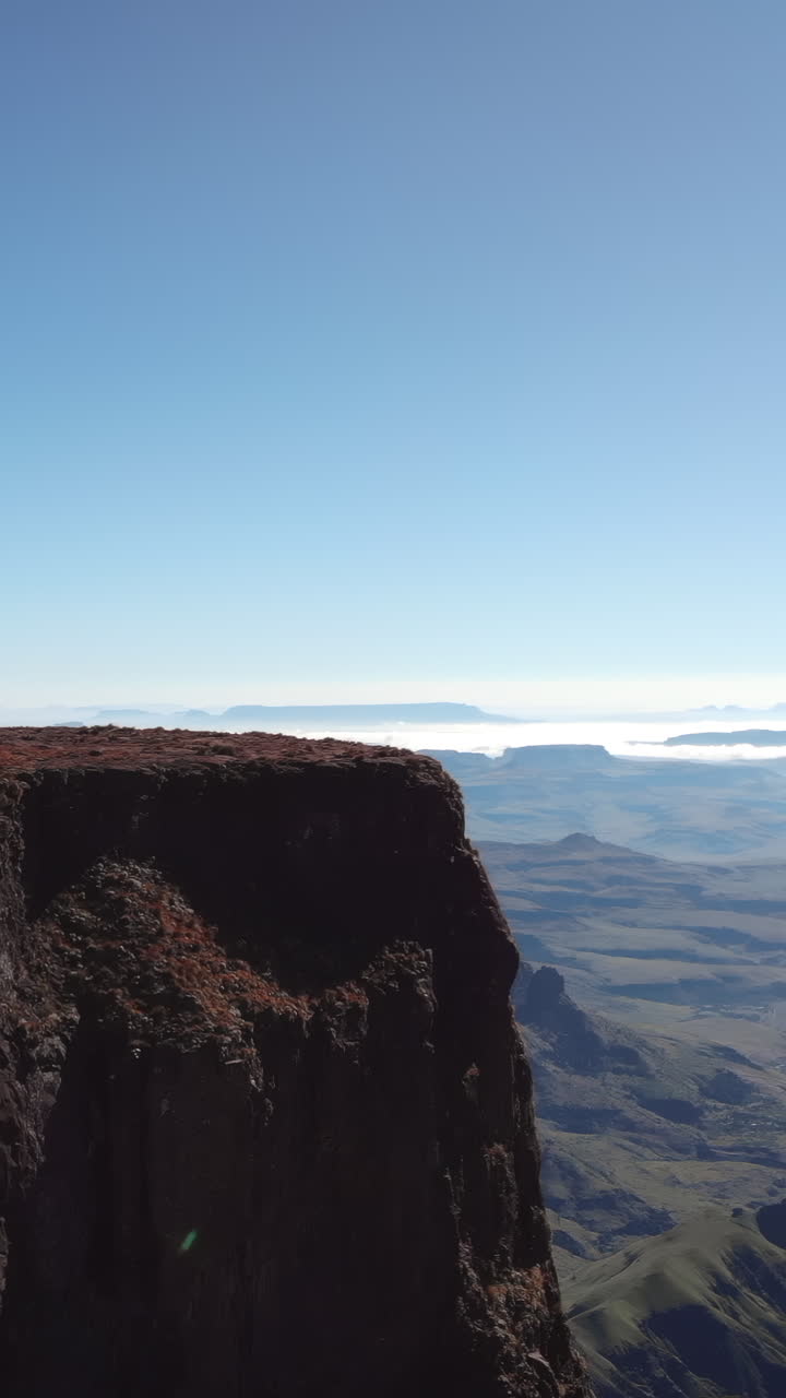 Maestoso paesaggio montano con bordo scogliera e valli distanti sotto un cielo azzurro limpido