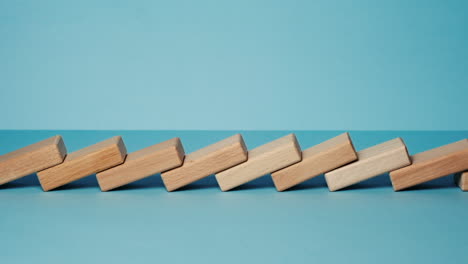 domino effect, row of wooden domino falling down with light blue background