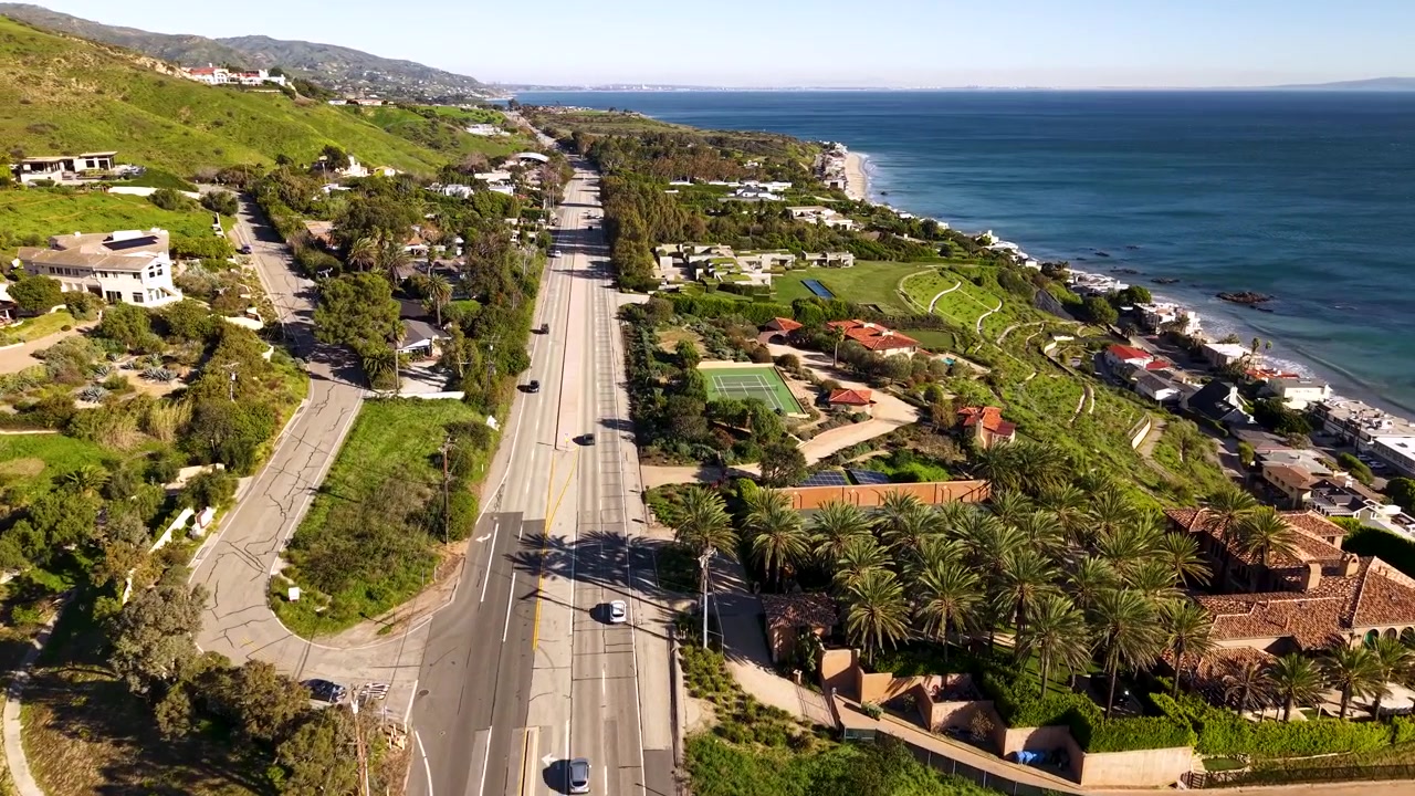 Lussuose ville di Malibu costeggiano la Pacific Coast Highway in una vista aerea con drone, le proprietà immobiliari di lusso fronte mare delle celebrità visibili direttamente dall'alto sull'iconica costa della California.