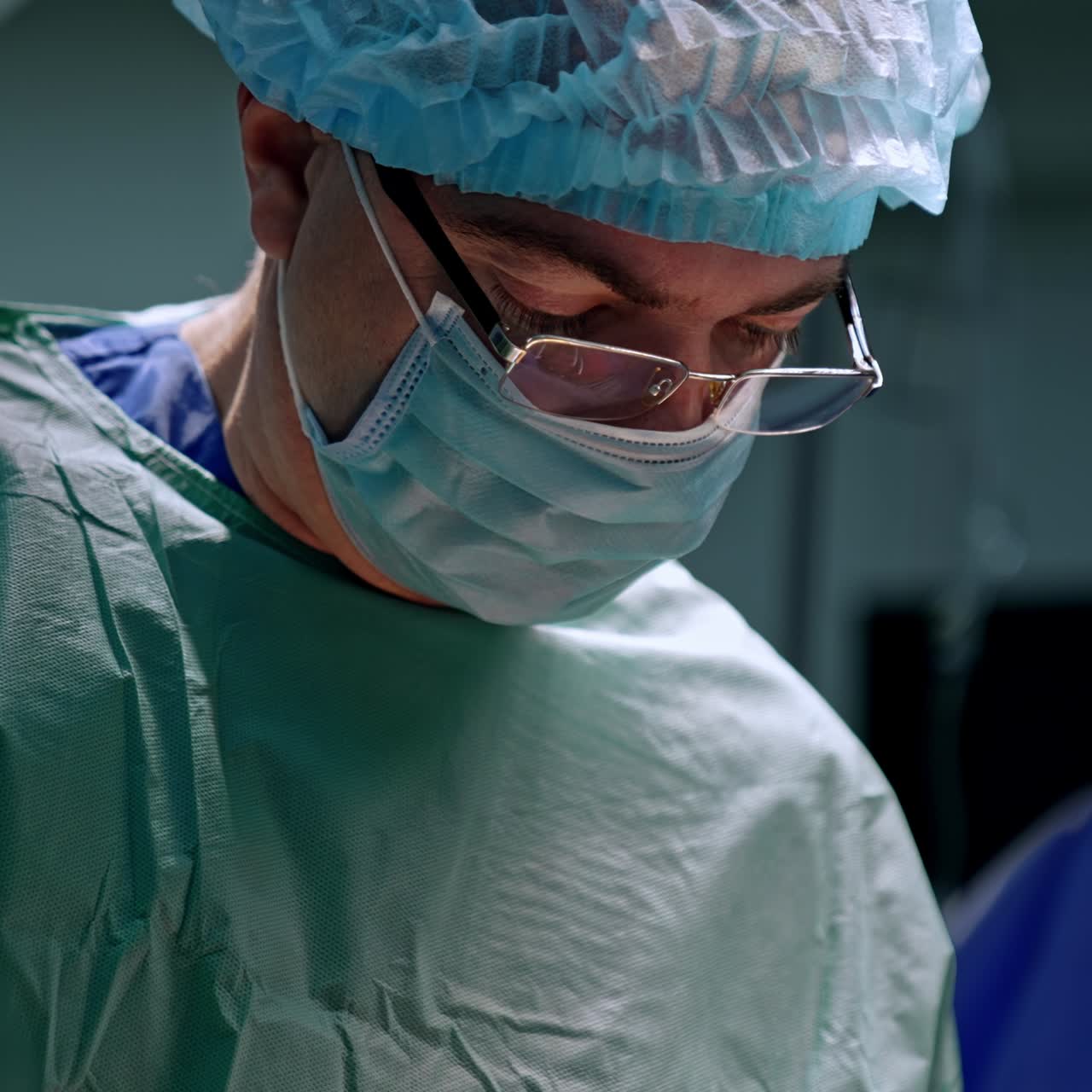 Adult male doctor wearing cap, mask, eyeglasses and uniform. Portrait of a surgeon working at operation. Close up