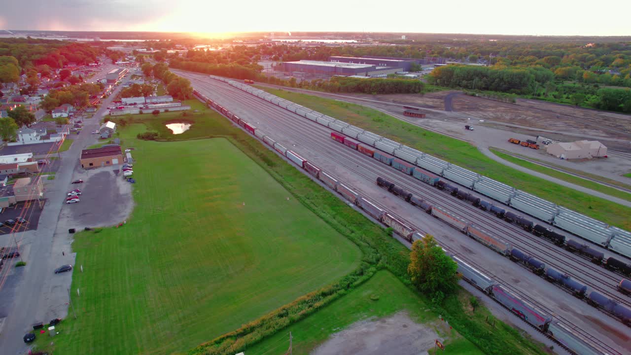해가 지는 동안 미국의 철도 야드와 주변 지역의 공중 풍경, 산업 풍경과 트랙을 보여줍니다.