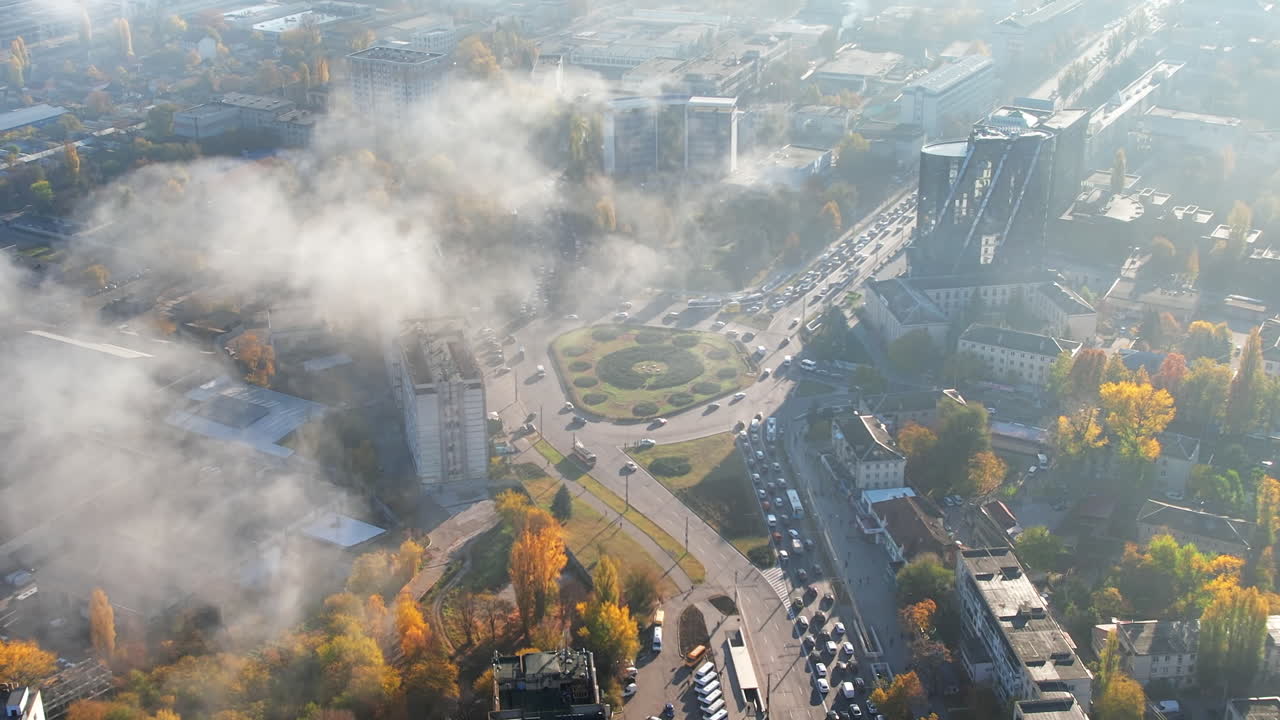 Aerial drone view of Chisinau at sunrise, Moldova. View of the city with fog in the air, multiple buildings, streets with cars and yellowed trees
