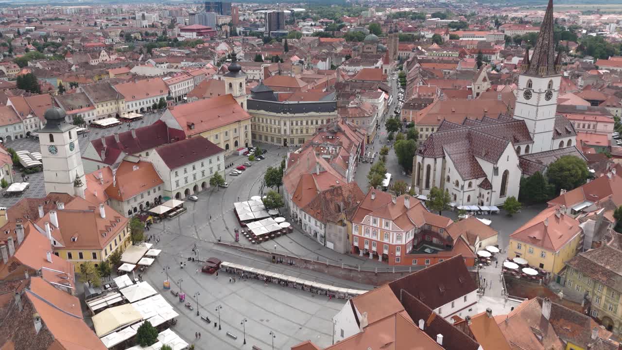 Dron lecący tyłem nad sybińskim Piața Mică, ukazujący zabytkową architekturę i kolorowe budynki starego miasta