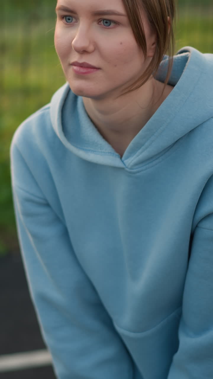 primer plano de una joven con el cabello atado hacia atrás, jugando al voleibol, centrándose en la sesión de entrenamiento, intenta atrapar la pelota voladora, con un campo abierto y una valla de barra en el fondo