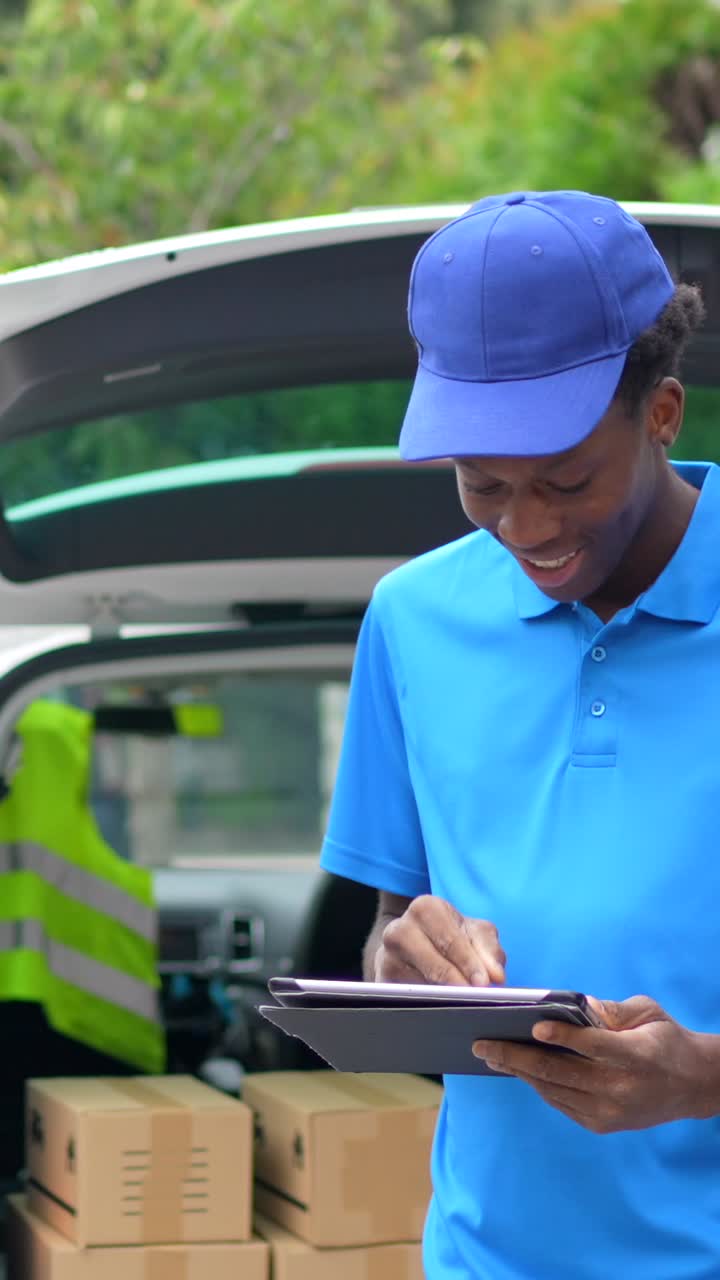Delivery person using tablet near van with packages