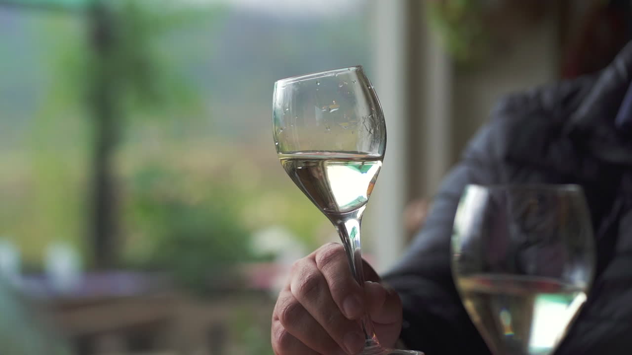 Hænder holder glas med hvidvin og skåler