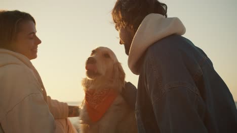 close-up shot of a couple having a picnic with their dog on a sunny beach in the morning