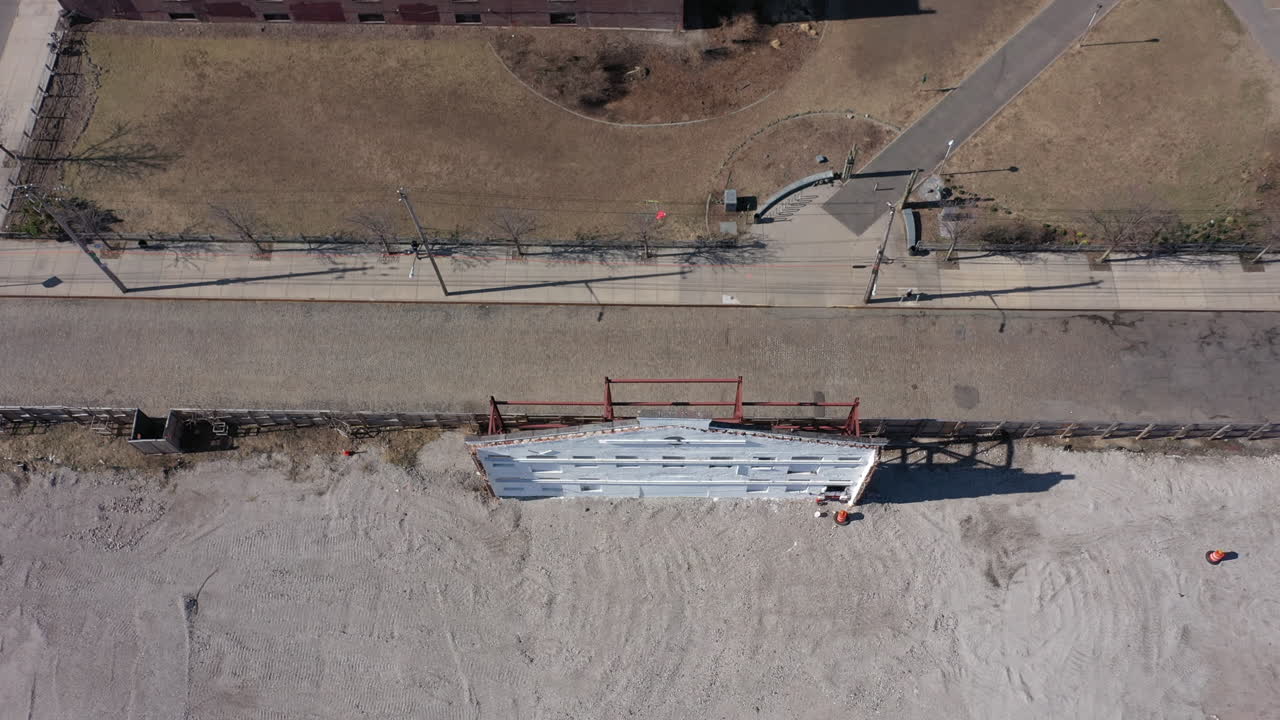 un tiro de arriba hacia abajo de una fachada de edificio, pintado de blanco con vigas de acero rojo en el otro lado