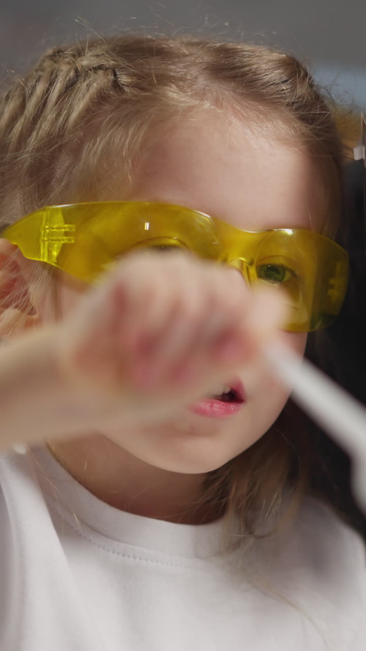 Funny brave girl student adds catalyst powder heap into bottle neck doing scientific experiment near bearded African-American tutor closeup slow motion
