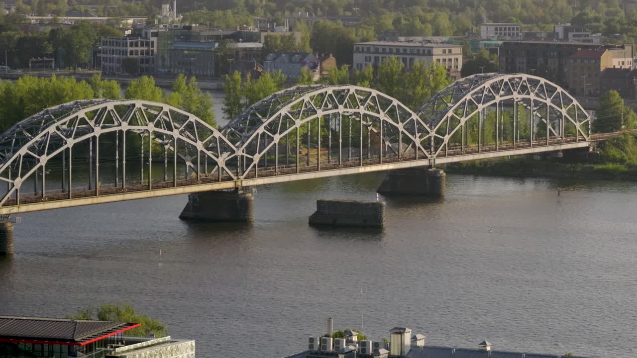 Cinematic pan following beautiful flying birds over river with bridge at sunset