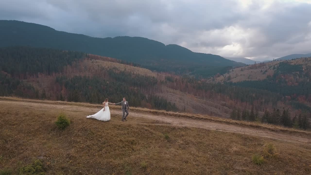 recién casados novia novio caminando por la ladera de la montaña, haciendo un beso, pareja de bodas familia, vista aérea
