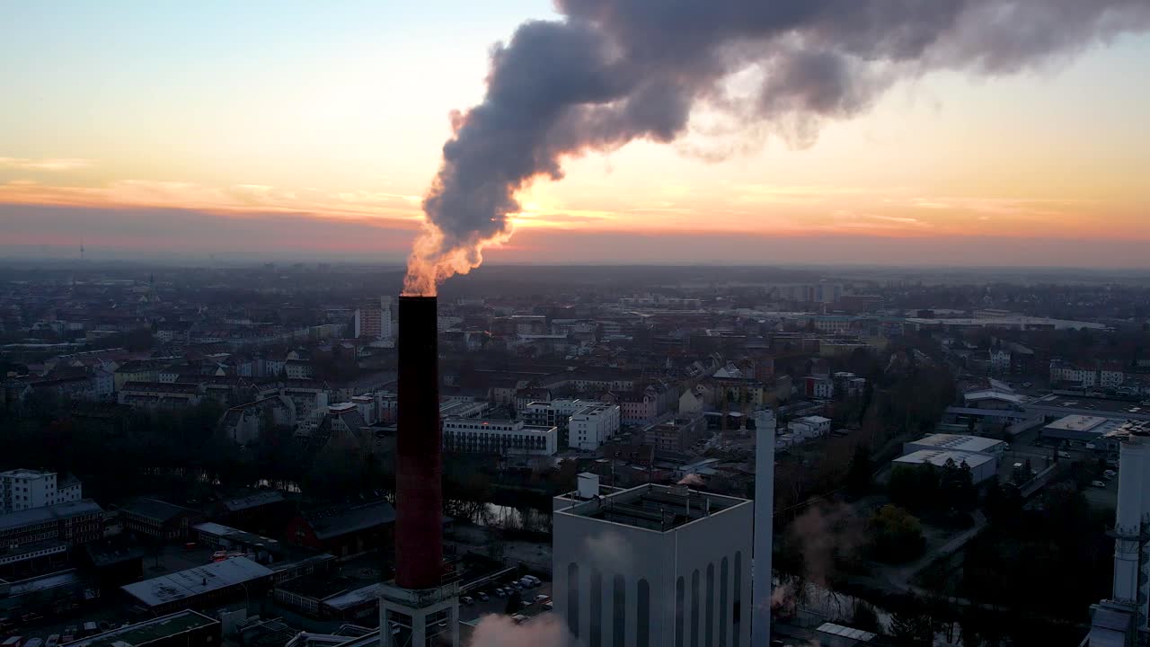 fumo scuro dalla ciminiera del propulsore con cielo di tonalità arancione sullo sfondo durante il tramonto a brunswick, germania