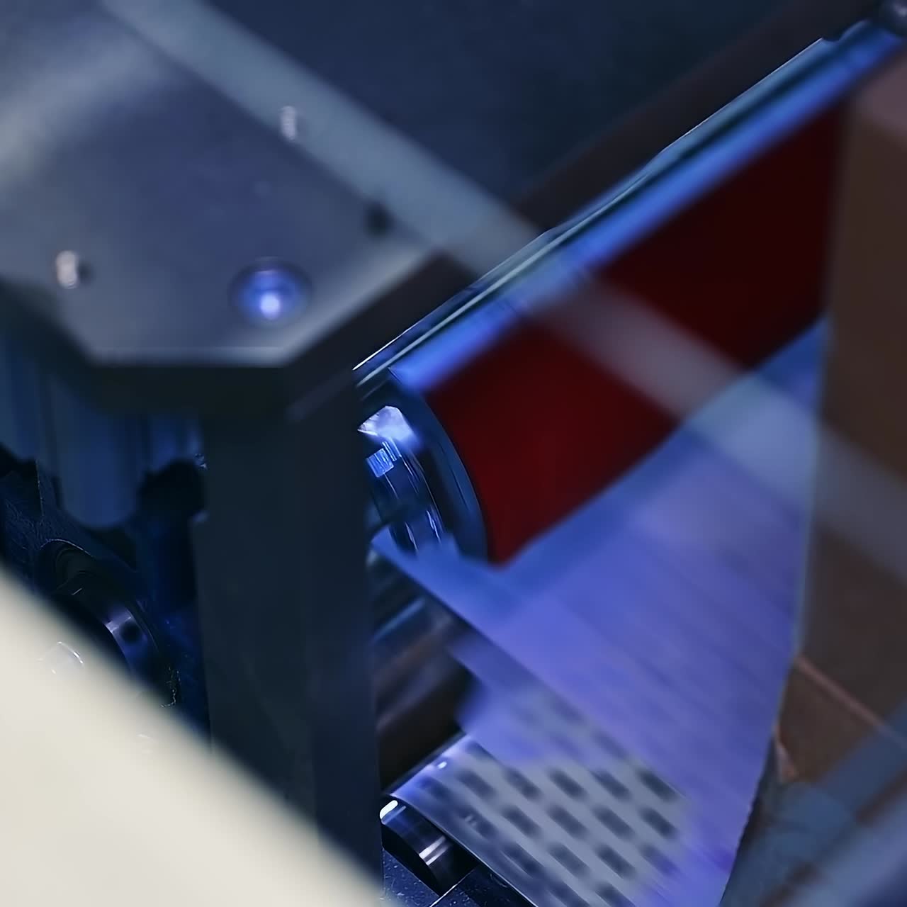 Enterprise for the production of diapers. Spinning shaft rotate and move the white layer along the conveyor line. Mechanism at work close up