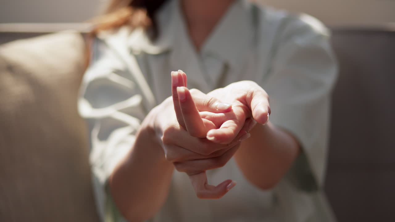 Slow-motion shot of a woman massaging her hands using her thumb to ease the pain that she is feeling.