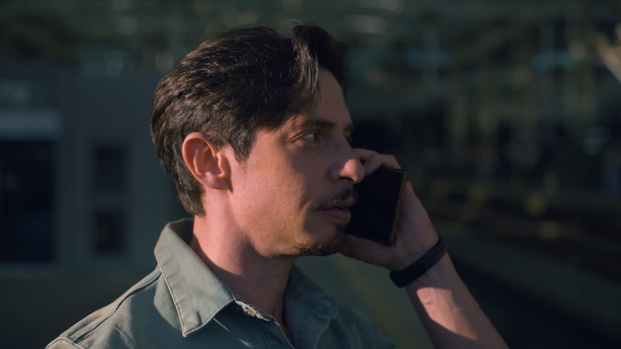 Handsome male traveler talking on his phone at Seoul train station, South Korea, urban setting, Medium profile as he nods pulling away