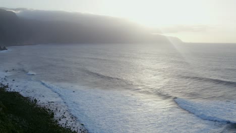 dramatic ocean waves crashing on a rocky coastline at sunset