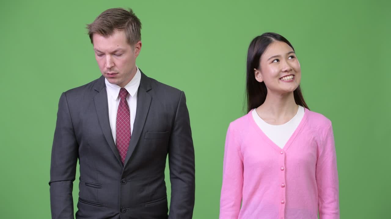 Young happy Asian woman and young sad businessman thinking together