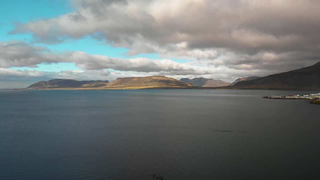 아이슬란드의 키르주펠 산에 가까운 공중 영상으로 탁 트인 바다, 산, 그룬다르피요르두르라는 작은 마을을 보여줍니다.