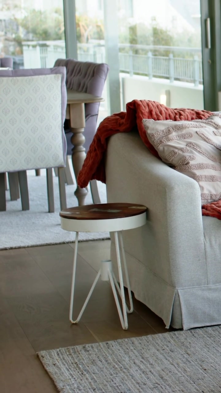 Vertical video: Panning camera revealing living-dining corner at home, showing sofa arm, side table