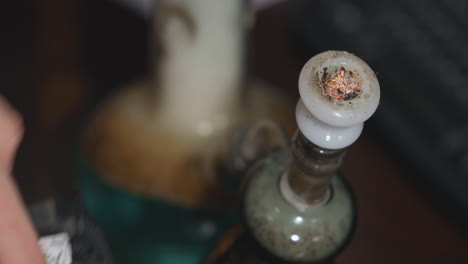 medical marijuana is lit and inhaled from a bong and cannabis smoke slowly falls