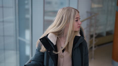 lady looking thoughtfully while resting her hand on iron rail in modern building with glass walls, lost in contemplation with subtle city background and natural light