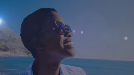 wearing sunglasses, smiling person relaxing by ocean on sunny day
