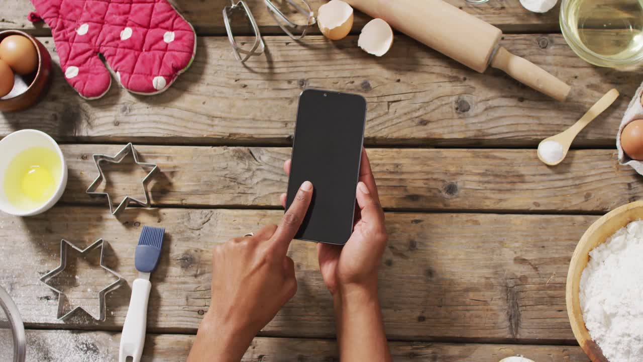 video de manos de una mujer sosteniendo un teléfono inteligente con espacio de copia sobre ingredientes y herramientas de horneado