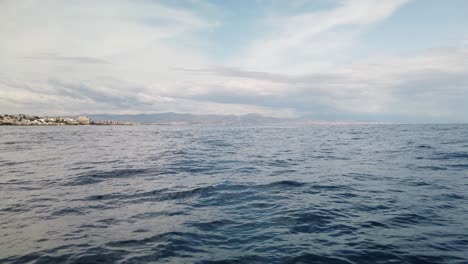 View-from-boat-on-sea-of-Costa-Del-Sol-Malaga-calm-ocean-water-surface-with-small-waves,-slow-motion