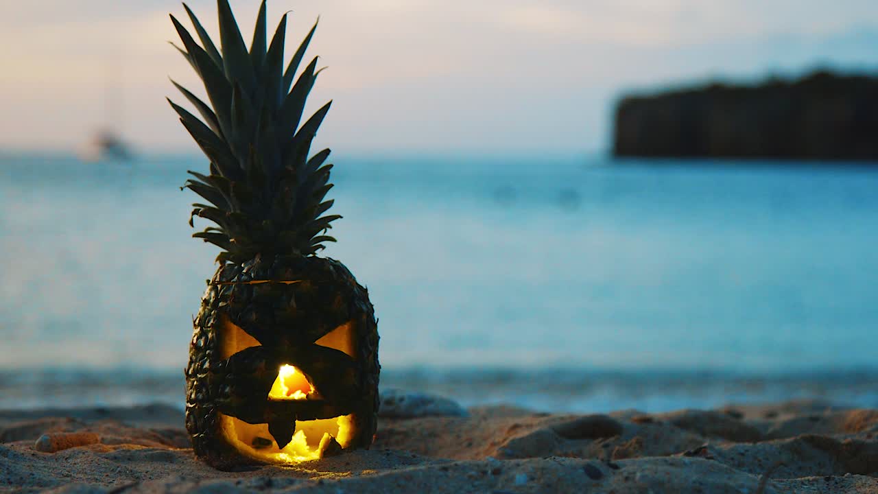 큐라소, 카리브해 섬 - 푸른 물과 범선을 배경으로 해변에 서 있는 할로윈 조각 파인애플의 가까운 풍경 - 클로즈업 샷