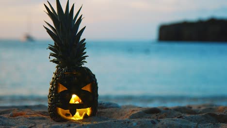 curacao, isla caribeña - un paisaje cercano de una piña tallada de halloween de pie en la playa con el fondo de agua azul y velero - primer plano