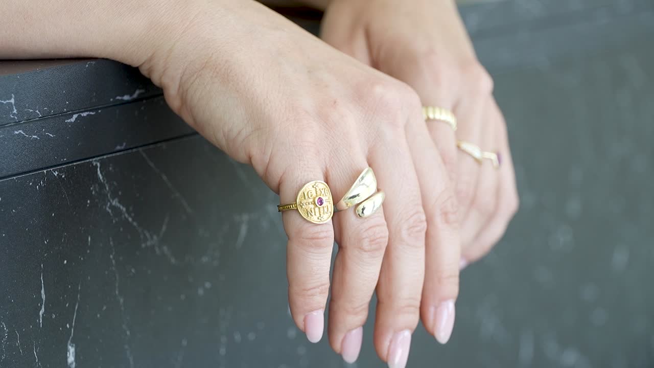 Close-up of hands adorned with stunning gold rings featuring various designs. The setting highlights the elegance of the jewelry and graceful fingers