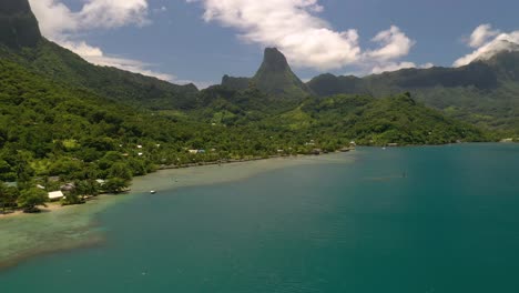 aerial shot flying over turquoise color sea towards mo'orea island coastline in french polynesia