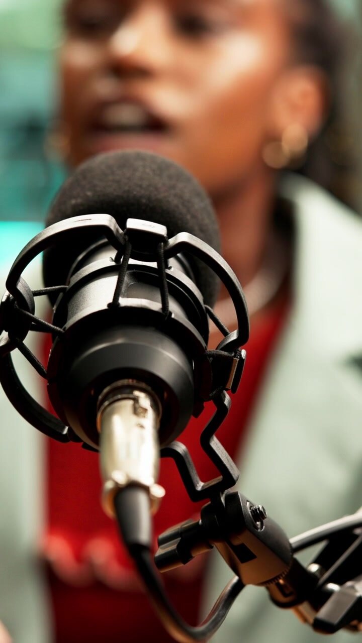 Giovane donna che parla in un microfono professionale in uno studio.
