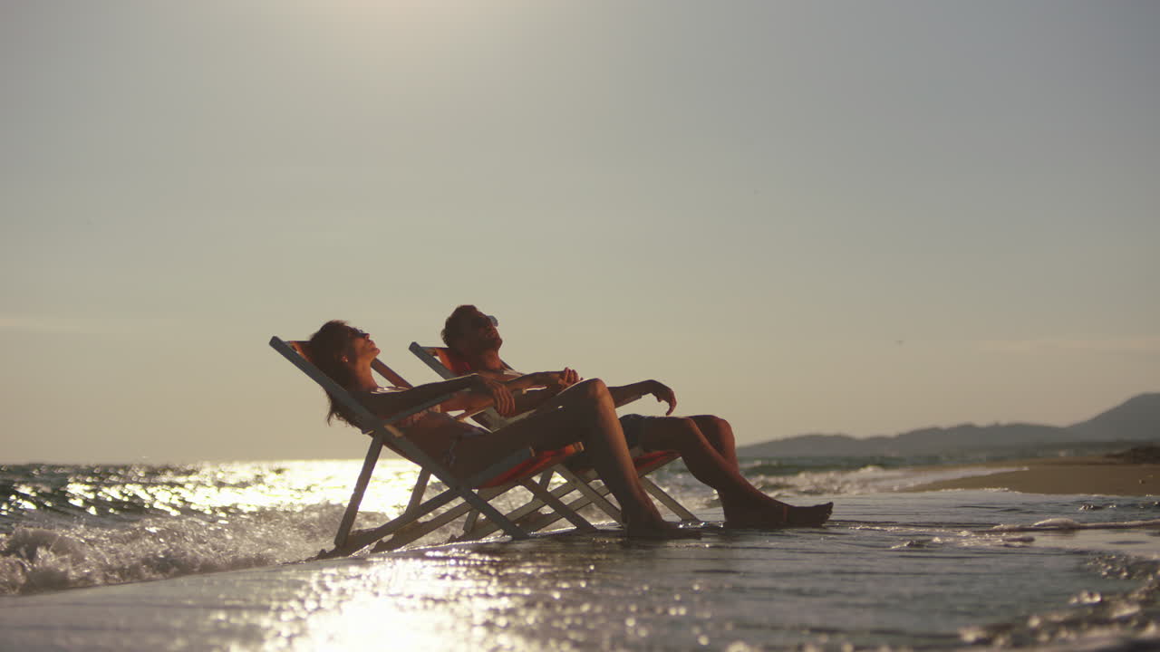 pareja relajándose en la playa al atardecer