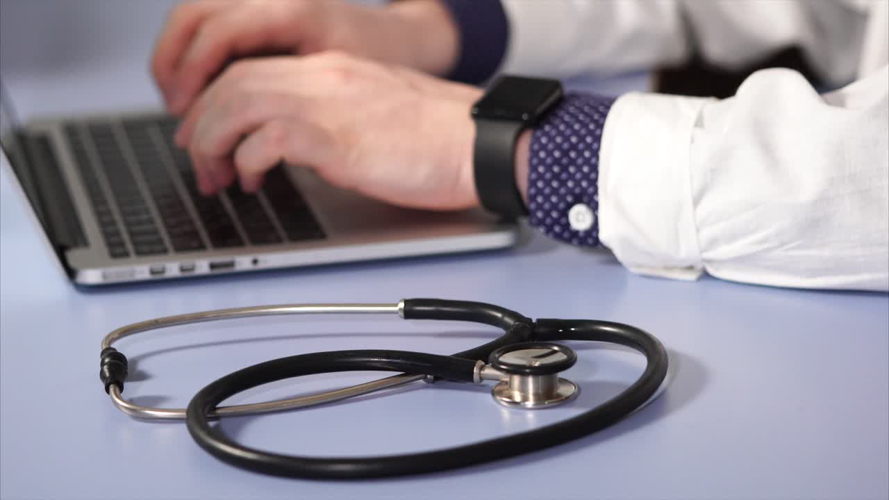 médico trabajando en una computadora portátil en una oficina