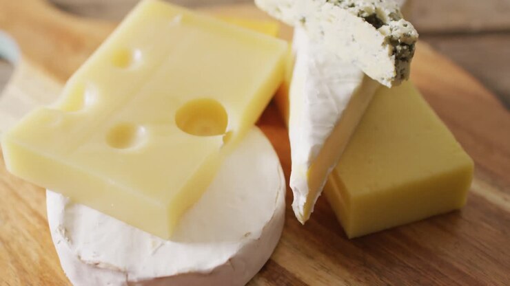 Video close up of assorted hard and soft cheeses on wooden chopping board
