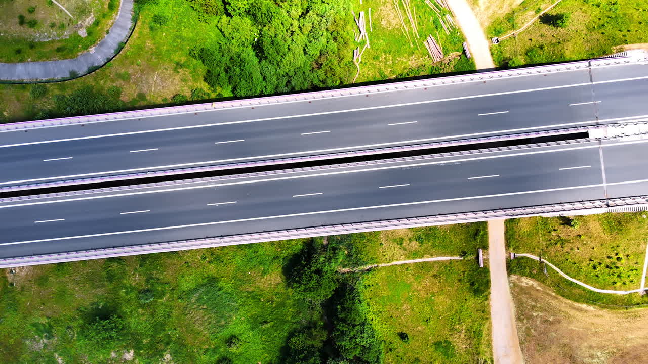 Rising above the modern freeways with some cars moving by. Greenery at backdrop. Road in the countryside.