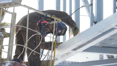 construction worker welding metal beams on a high-rise building in winter
