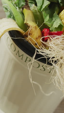 vídeo de un contenedor de compost blanco con residuos orgánicos sobre un fondo de madera