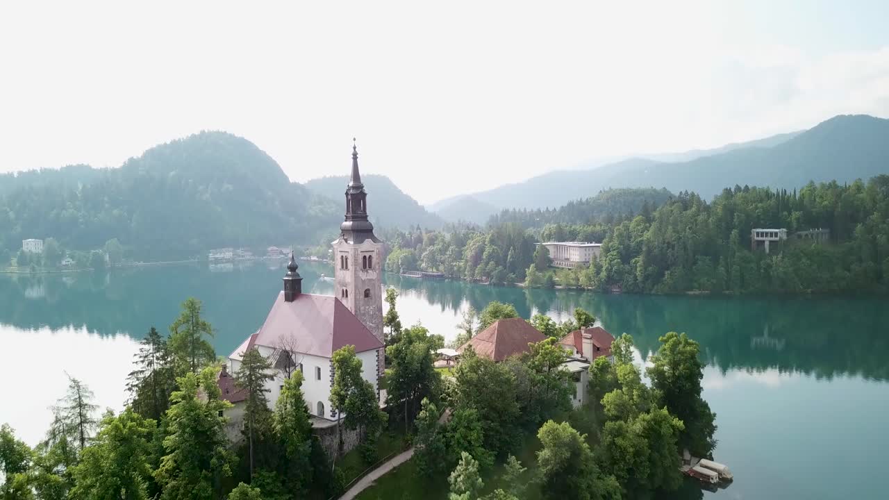 Ripresa aerea che si allontana da una chiesa su un'isola in Slovenia.