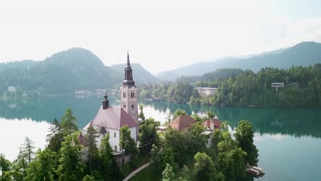 aerial shot pulling away from a church on an island in slovenia