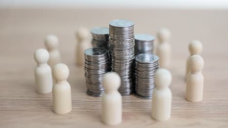 wooden figures encircling stacks of coins, representing finance and collective investment