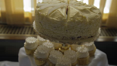 wedding cake and cupcakes sitting next to a window