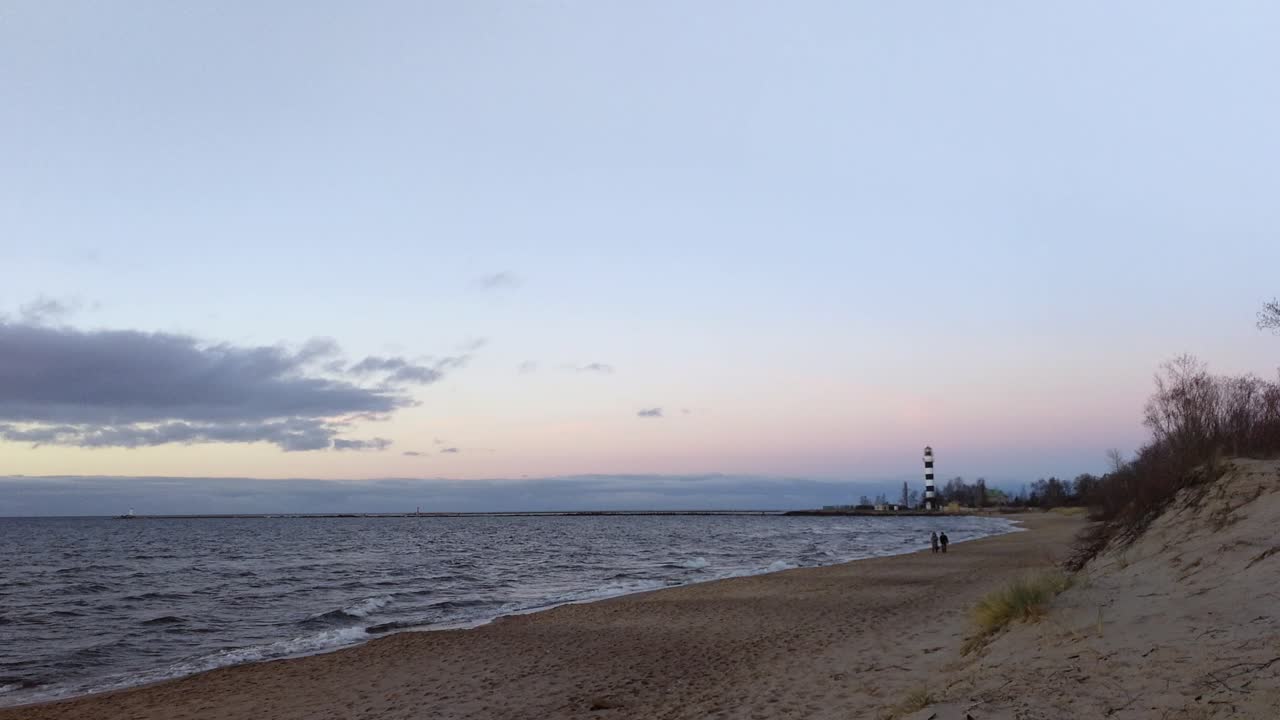 일몰 동안 바다 근처를 걷는 사람들