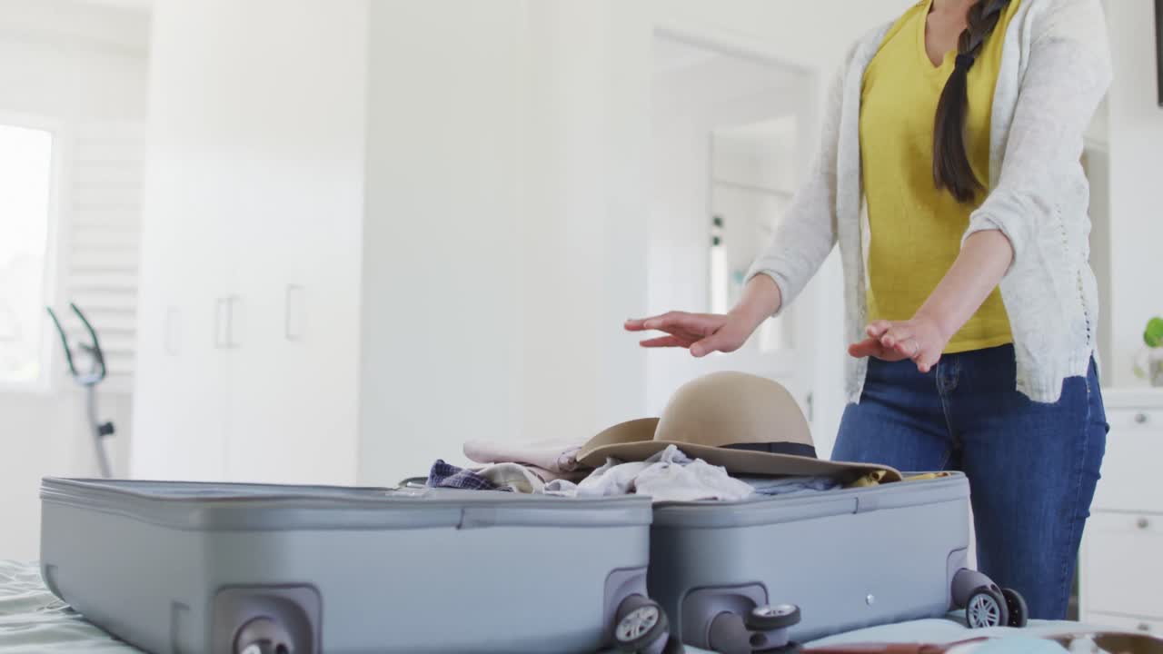 mujer asiática feliz preparando ropa y maleta para viajar