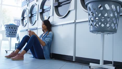 woman using mobile phone at laundromat 4k