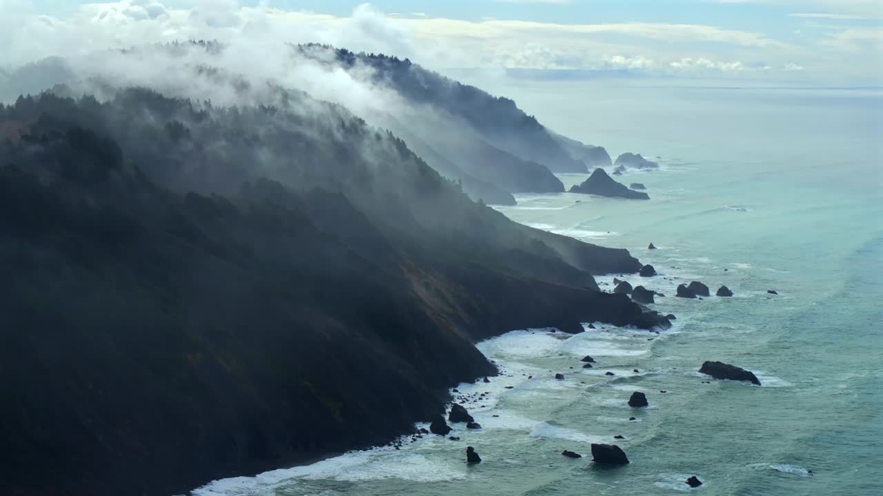 Rugged coastline Lost Coast Trail USAL Beach campground 4wd black sand mist rain fog aerial drone California PNW waves crashing cloud layer morning Chimney Rocks nature landscape backwards motion
